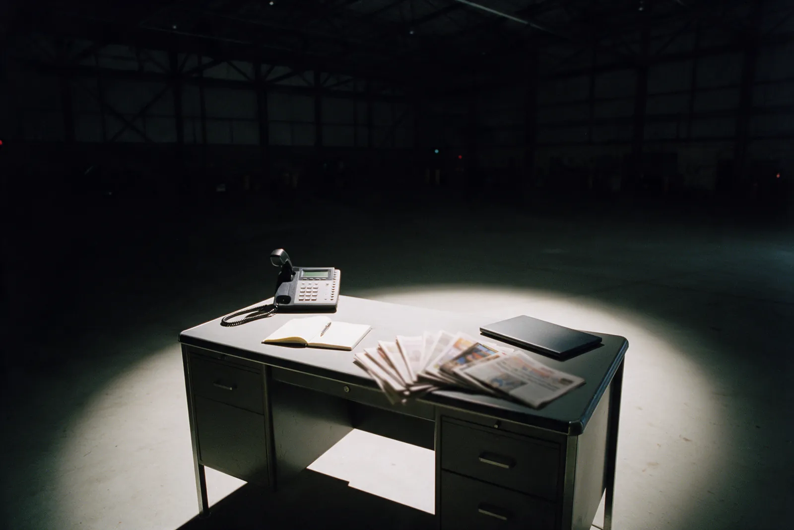 A press desk with a phone off the hook and a stack of newspapers.
