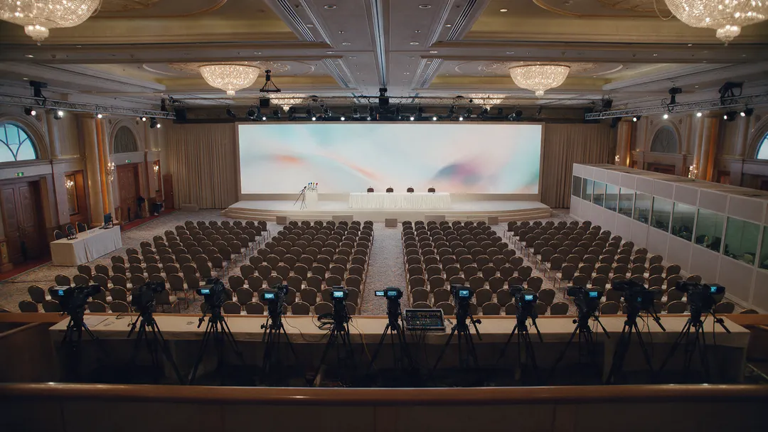 Example press conference in a hotel ballroom, seen from the balcony before the doors open to the media.